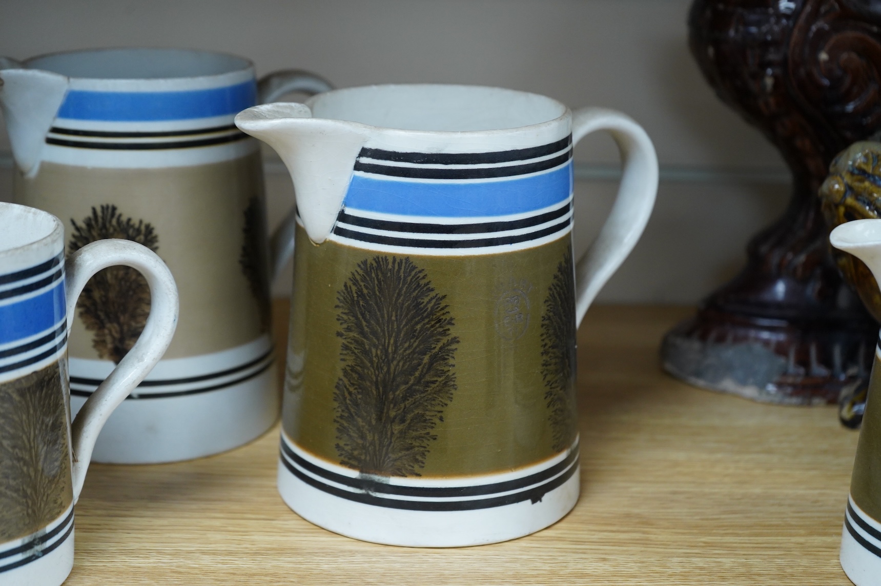Three early 19th century Mocha ware jugs and a mug, largest 16cm high